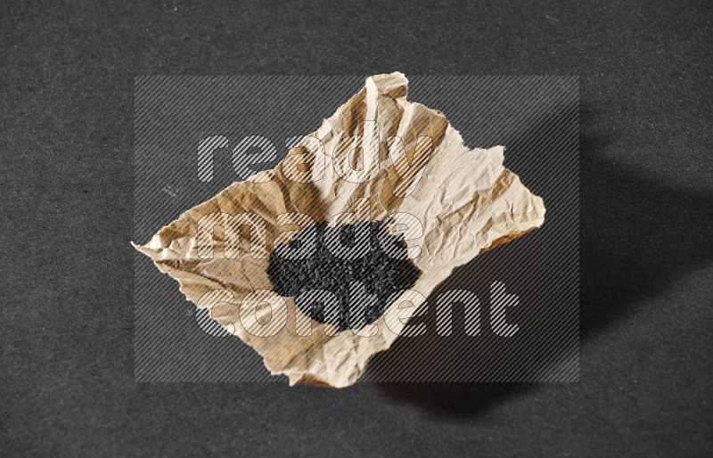 بذور حبة البركة في قطعة من الورق علي خلفية سوداء