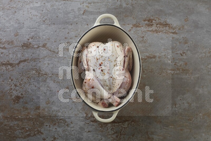whole raw chicken on in a white ceramic pot direct on a rustic grey background