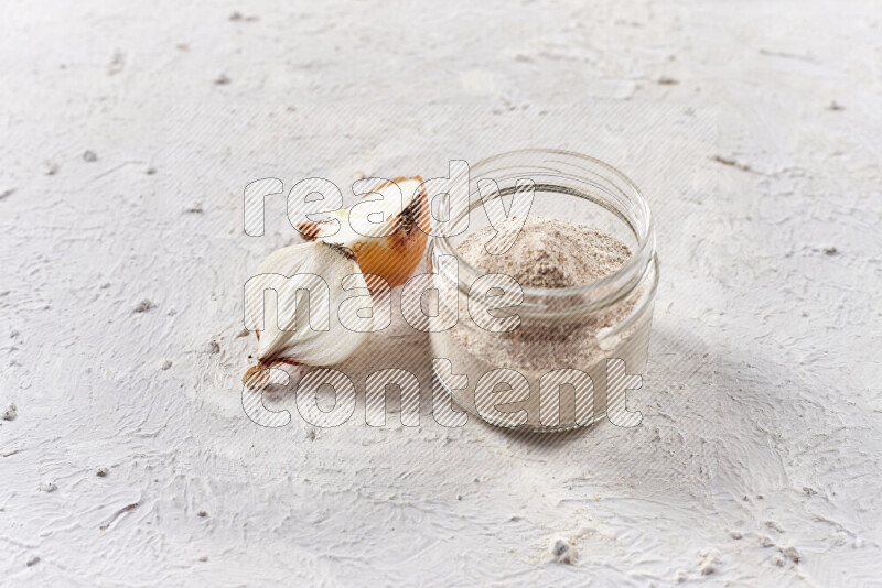 A glass jar full of onion powder on white background