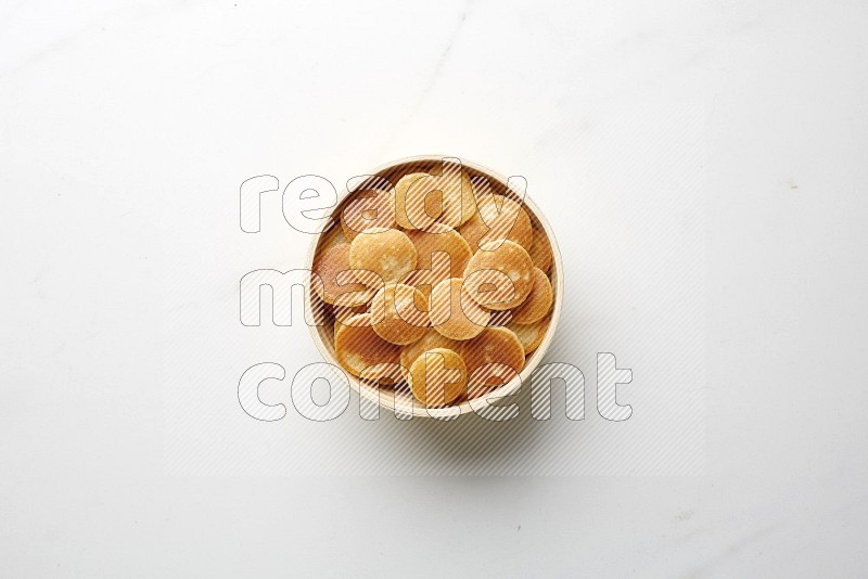 Top-view shot of plain cereal pancakes in a round bowl on white background