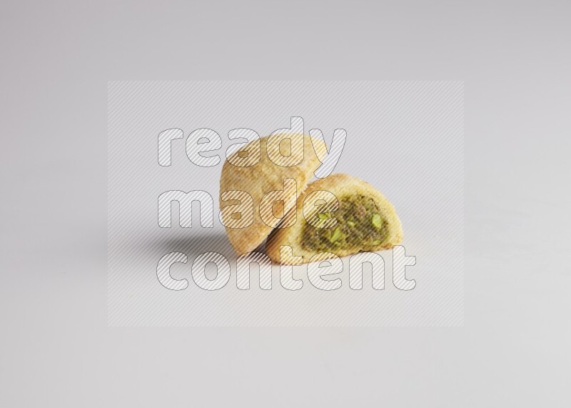 Two Pieces of Maamoul filled with pistachio paste  one of them is cut direct on white background