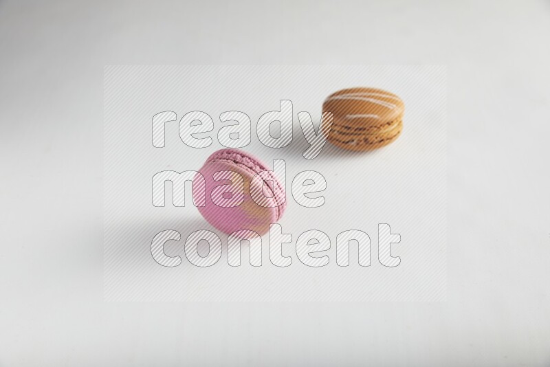 45º Shot of of two assorted Brown Irish Cream, and Purple Strawberry macarons on white background