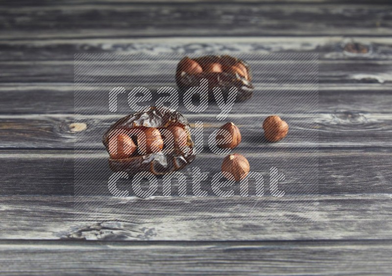 two hazelnut stuffed madjoul dates on a wooden grey background