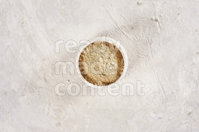 A beige pottery bowl full of ground ginger powder on white background