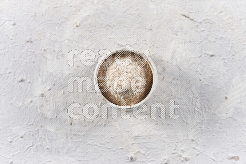 A beige pottery bowl full of onion powder on white background