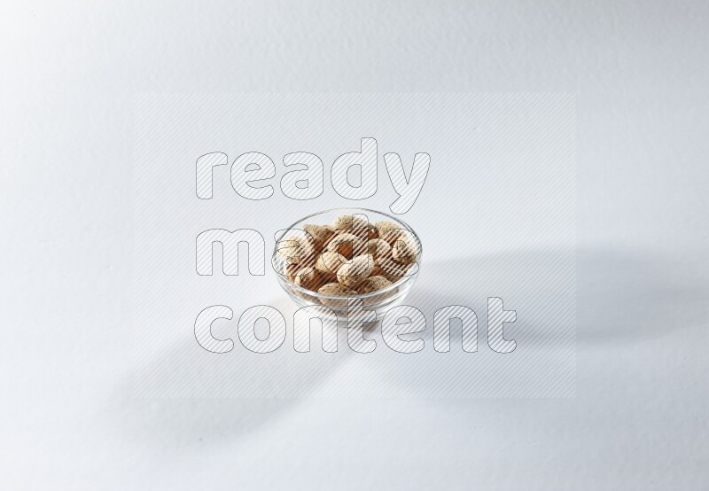 A glass bowl full of almonds on a white background in different angles