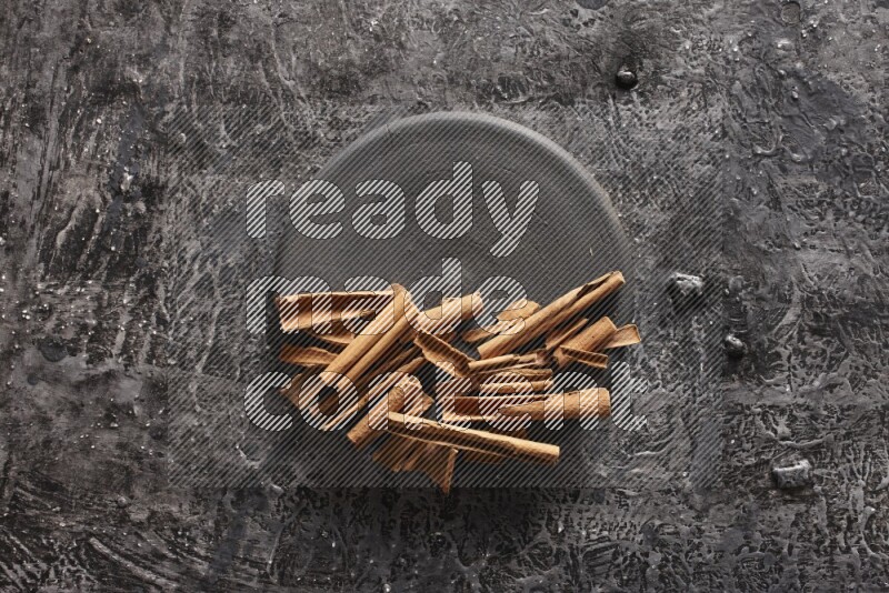 cinnamon sticks on a black plate on textured black background