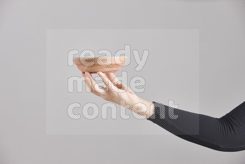 A woman in black abaya holding different wooden essentials in different positions