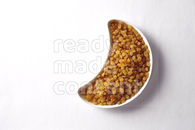 Raisins in a crescent pottery plate on white background