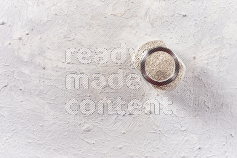 A glass jar full of onion powder on white background