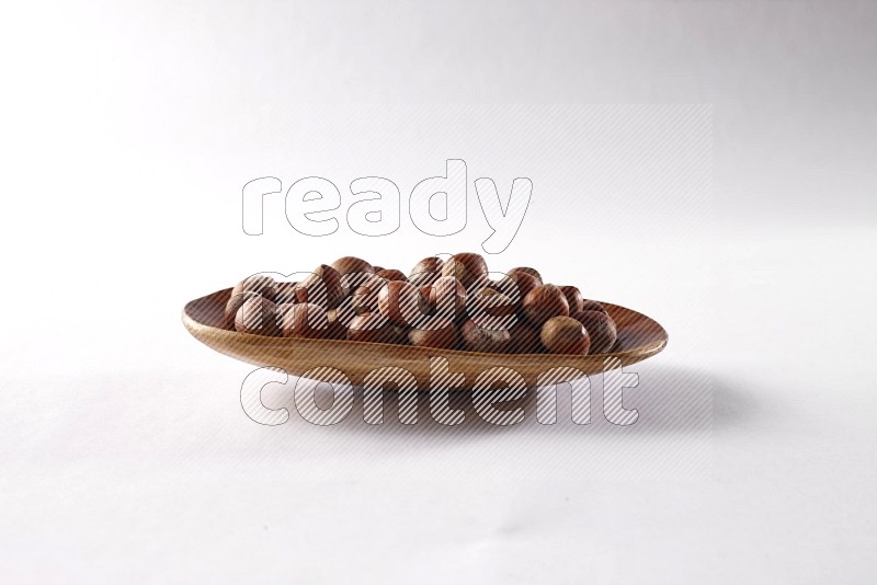 Hazelnuts in a wooden plate on white background