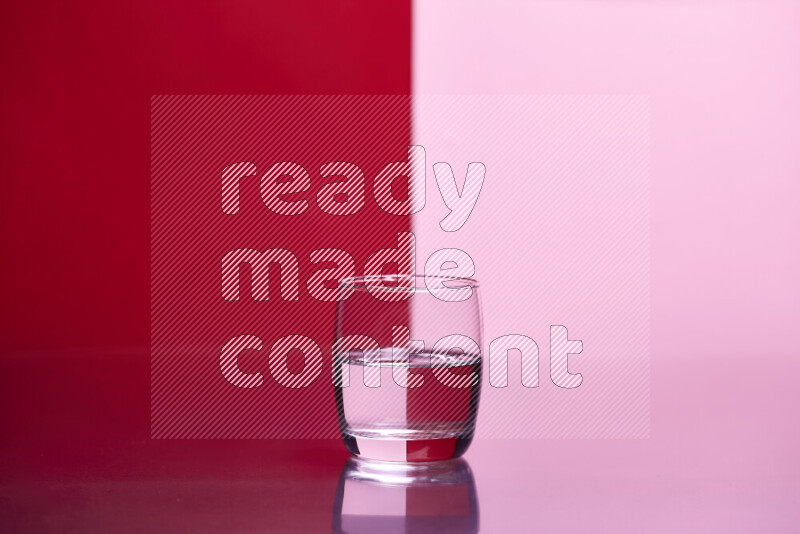 The image features a clear glassware filled with water, set against red and rose background