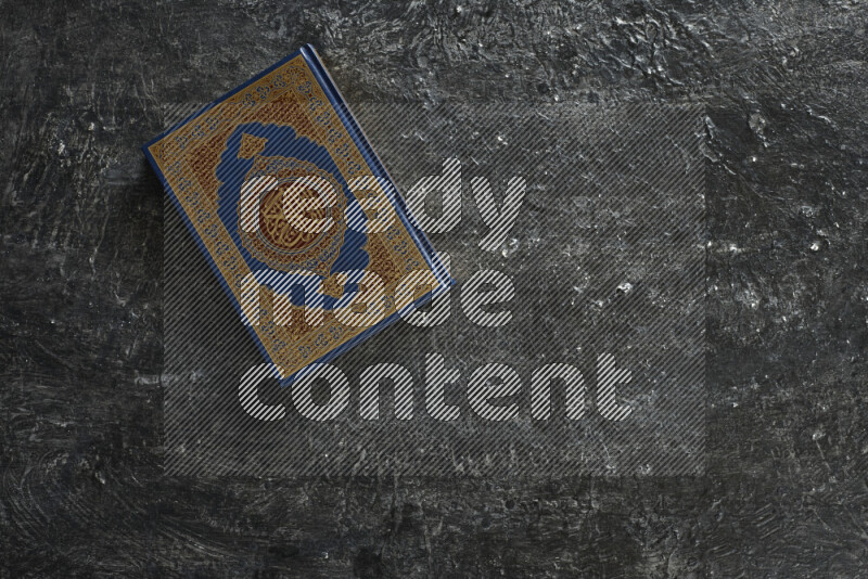 Quran with a prayer beads on textured black background