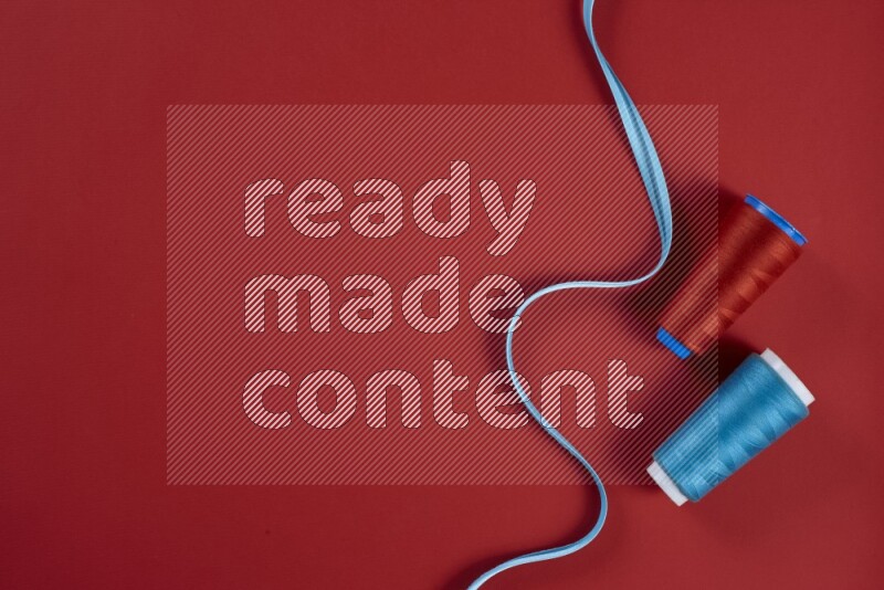 مجموعة من أدوات الخياطة والتفصيل زرقاء وحمراء اللون على خلفية حمراء