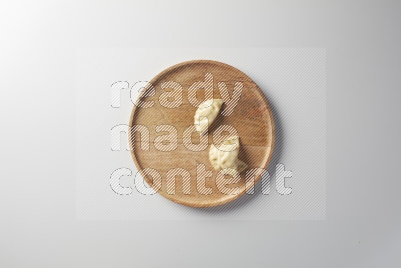 Three Sambosas on a wooden round plate on a white background