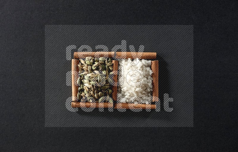 2 squares of cinnamon sticks full of white salt and cardamom on black flooring