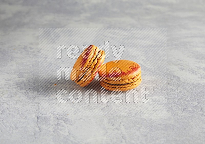 45º Shot of two orange Exotic macarons on white  marble background