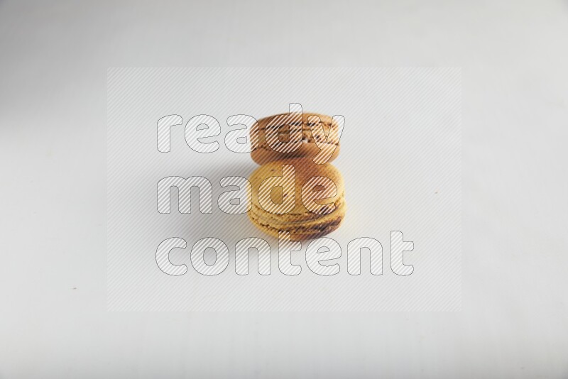 45º Shot of of two assorted Brown Irish Cream, and Yellow Crème Brulée macarons on white background