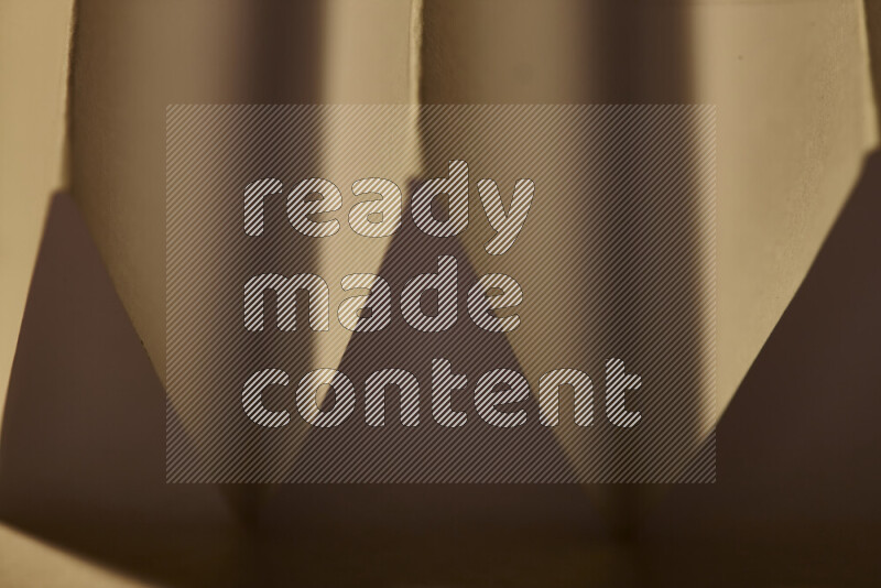 A close-up abstract image showing sharp geometric paper folds in warm gradients