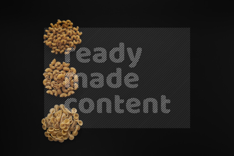 Different pasta types in 3 bunches on black background