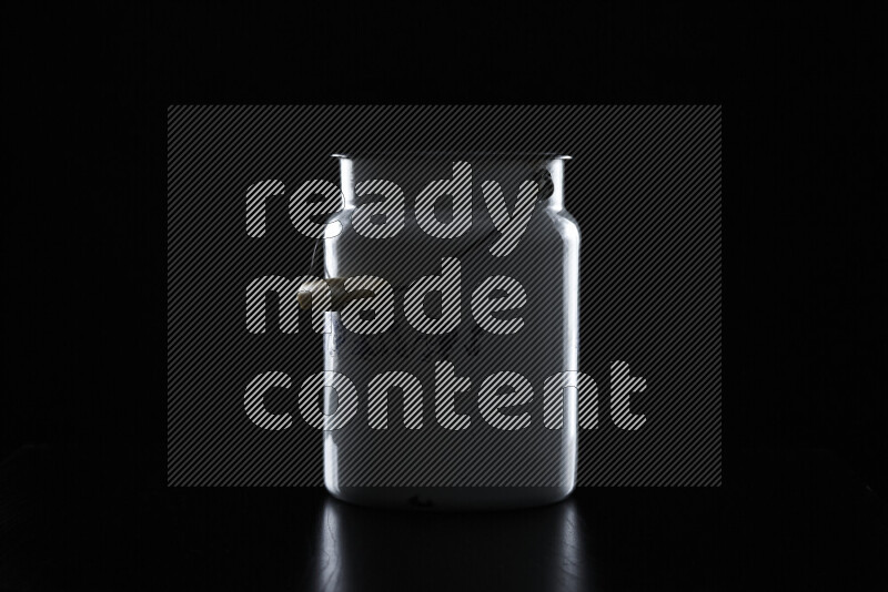 A vintage milk canister with colored rim light against black background