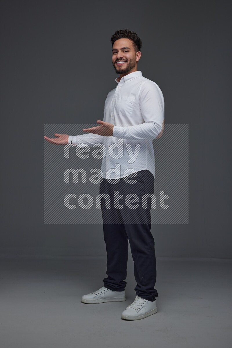 A man wearing smart casual standing and making multi hand gestures eye level on a gray background