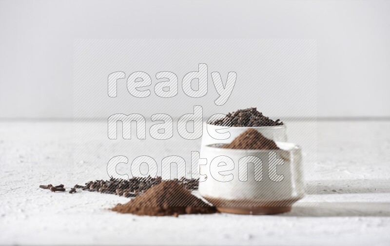 وعاءين من السيراميك بيج اللون، أحدهما مملوء بالقرنفل والآخر مملوء بالبودرة على أرضية بيضاء