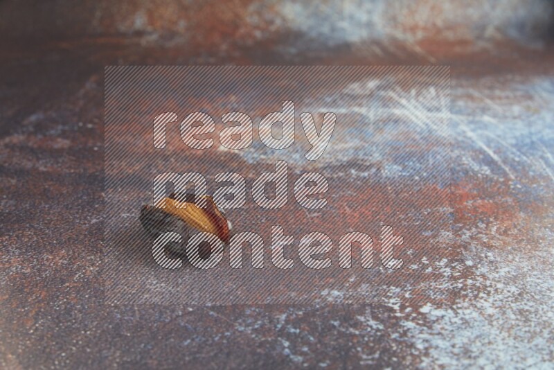 one almond stuffed madjoul date on a rustic reddish background