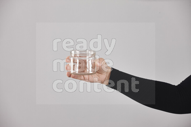 A woman in black abaya holding different glassware in different positions