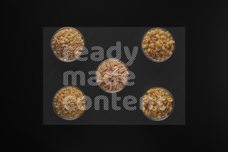 أنواع مختلفة من المعكرونة في أوعية زجاجية علي خلفية سوداء