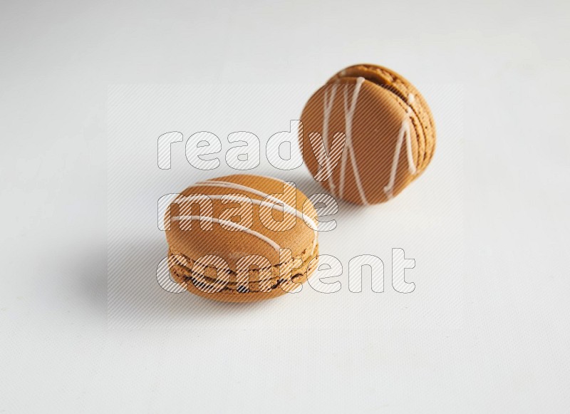 45º Shot of two Brown Irish Cream macarons on white background