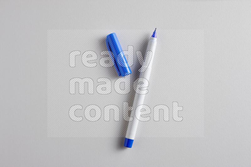 لقطة مقربة تظهر قلم تلوين واحد مفتوح بغطاء على خلفية رمادية
