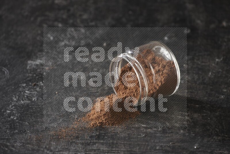 وعاء زجاجي مقلوب ممتلئ ببودرة القرنفل على أرضية سوداء