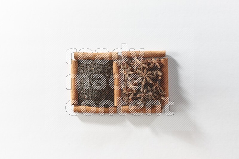 2 squares of cinnamon sticks full of star anise and black tea on white flooring