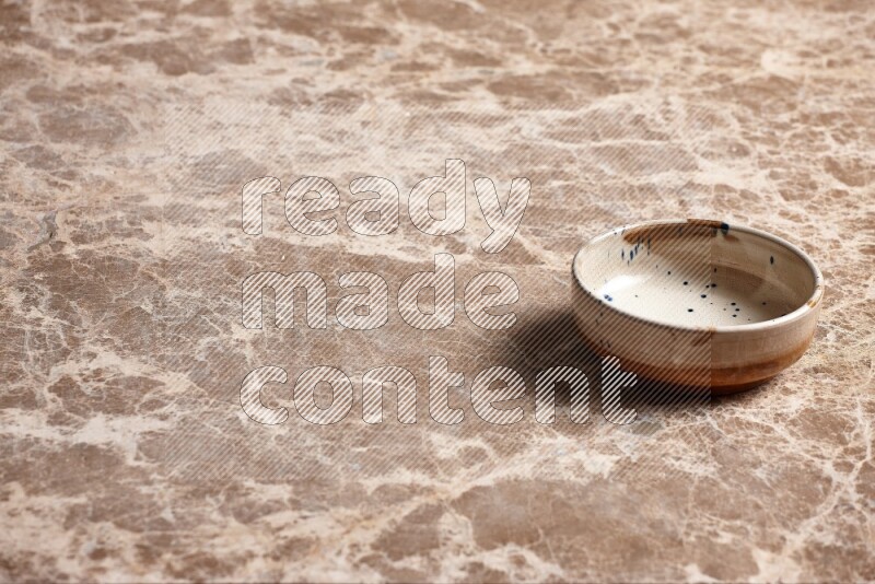 A multicolored pottery plate on beige marble background
