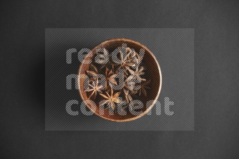 Star Anise in a wooden bowl on black flooring