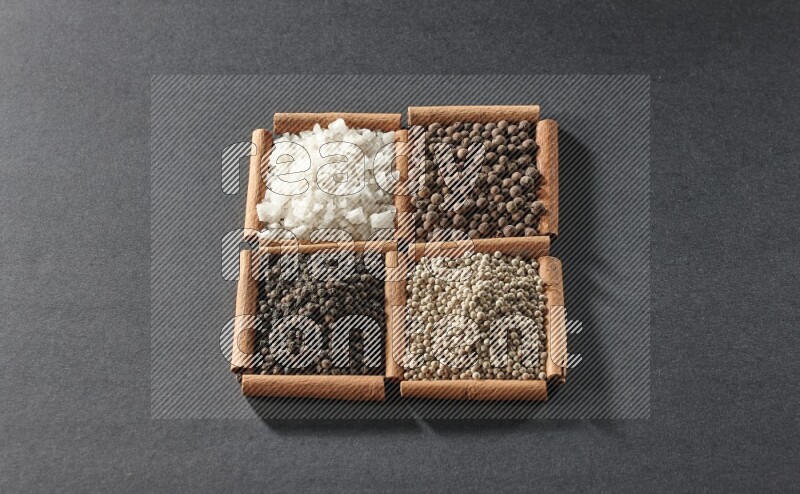 4 squares of cinnamon sticks full of black pepper, white pepper, allspice and white salt on black flooring