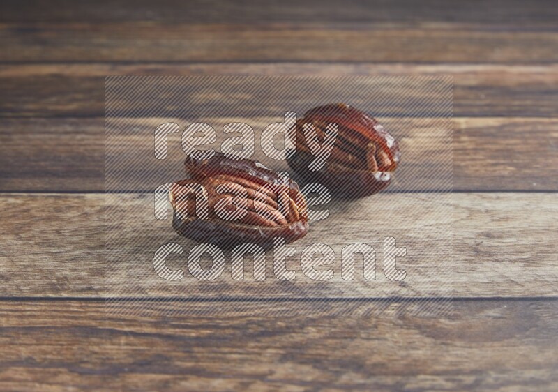 two pecan stuffed madjoul date on a wooden background