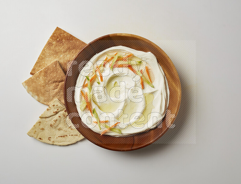 Lebnah garnished with sliced carrots & cucumber in a wooden plate on a white background