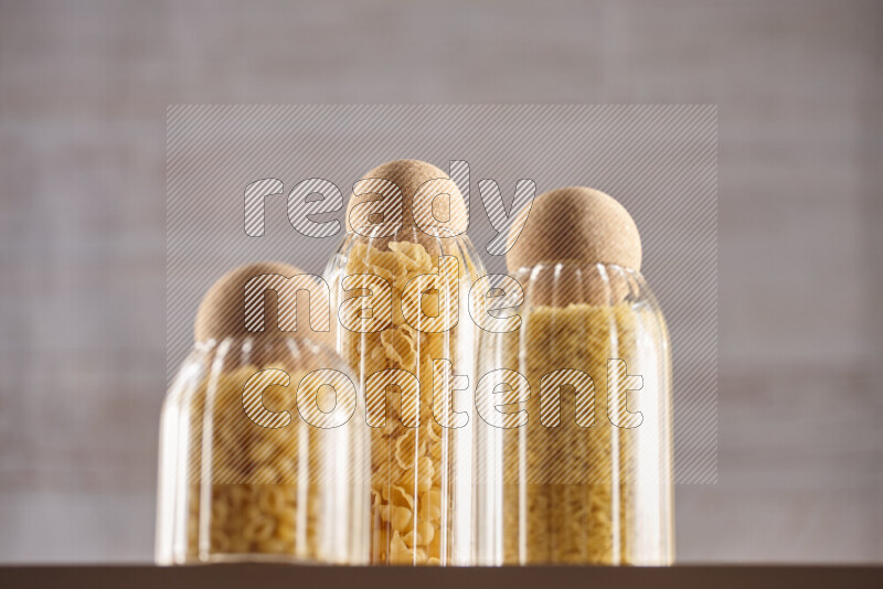Raw pasta in glass jars on beige background