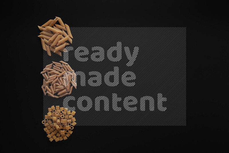 Different pasta types in 3 bunches on black background