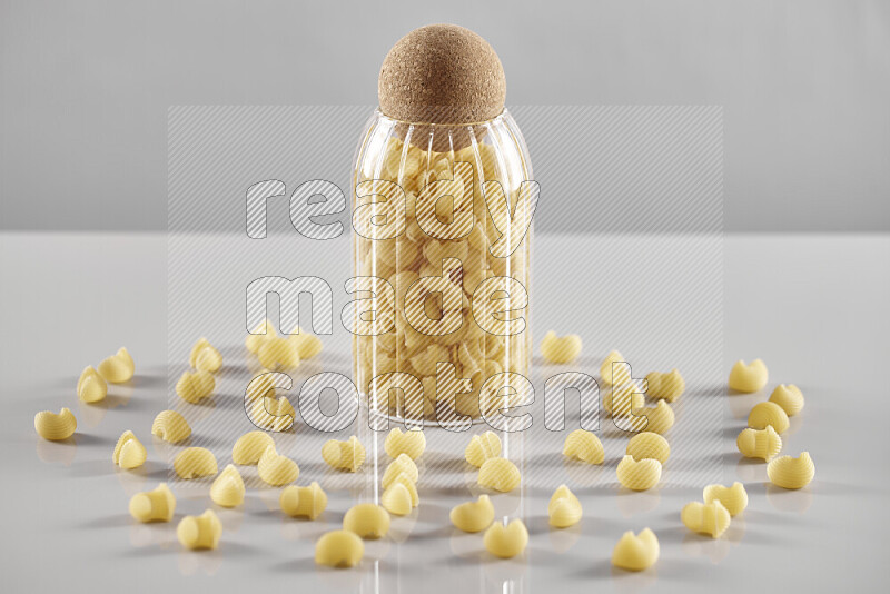 Raw pasta in a glass jar on light grey background