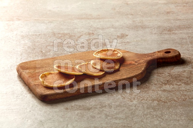 Five stacked plain mini pancakes on a wooden board on beige background