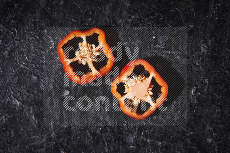 Red bell pepper slices on black background