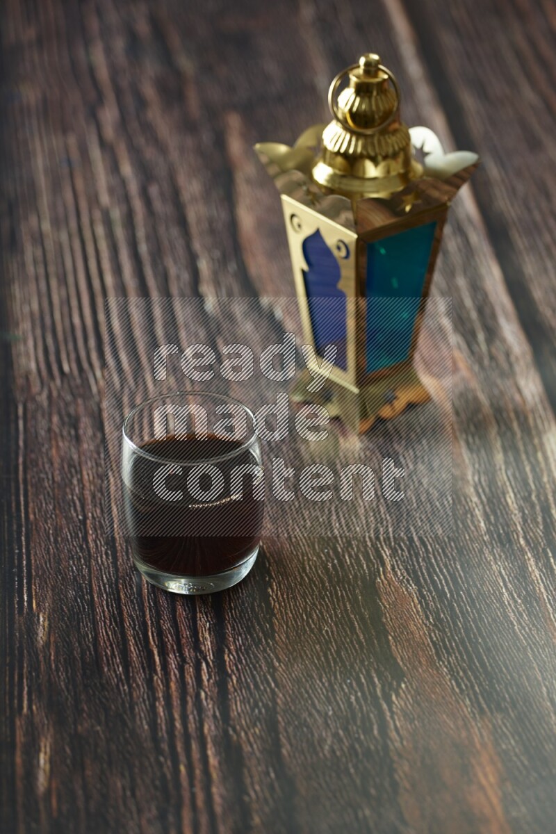 A golden lantern with different drinks, dates, nuts, prayer beads and quran on brown wooden background