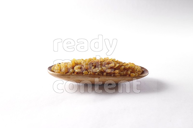 Raisins in a wooden plate on white background