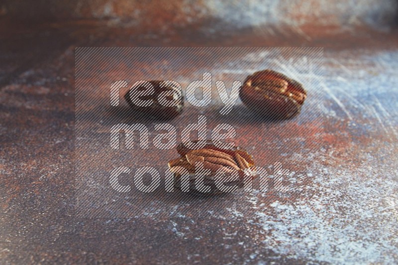 two pecan stuffed madjoul dates on a rustic reddish background