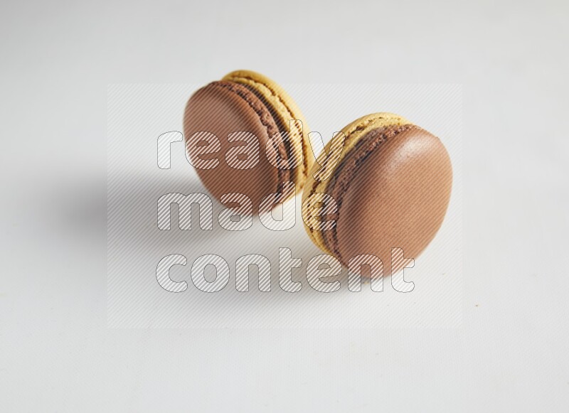 45º Shot of two Yellow and Brown Chai Latte macarons on white background
