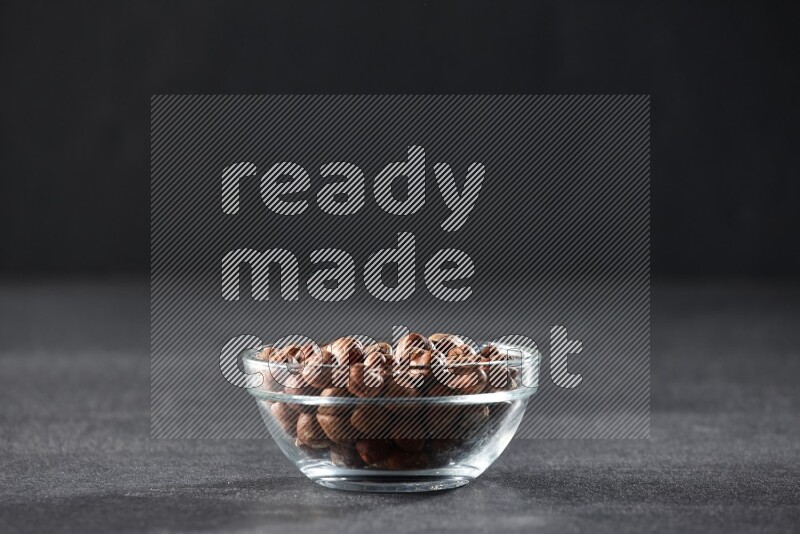 A glass bowl full of peeled hazelnuts on a black background in different angles