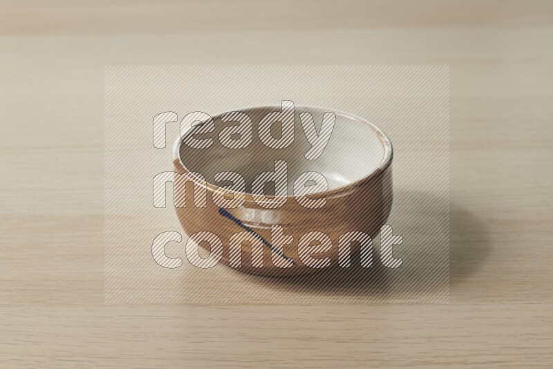 A multicolored pottery bowl on light wooden background